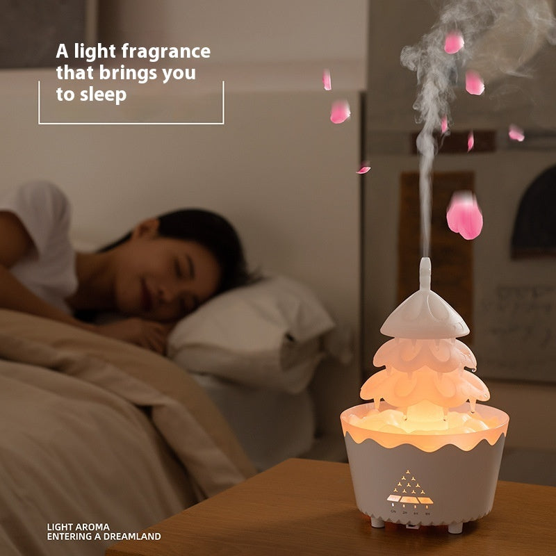 White Christmas tree aroma diffuser emitting mist with pink petals, beside sleeping woman in cozy bedroom