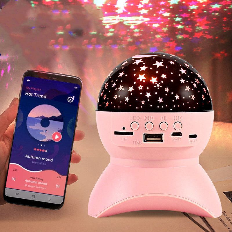 Pink Bluetooth speaker and star projector with star-shaped light patterns and smartphone playing music
