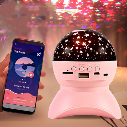 Pink Bluetooth speaker and star projector with star-shaped light patterns and smartphone playing music