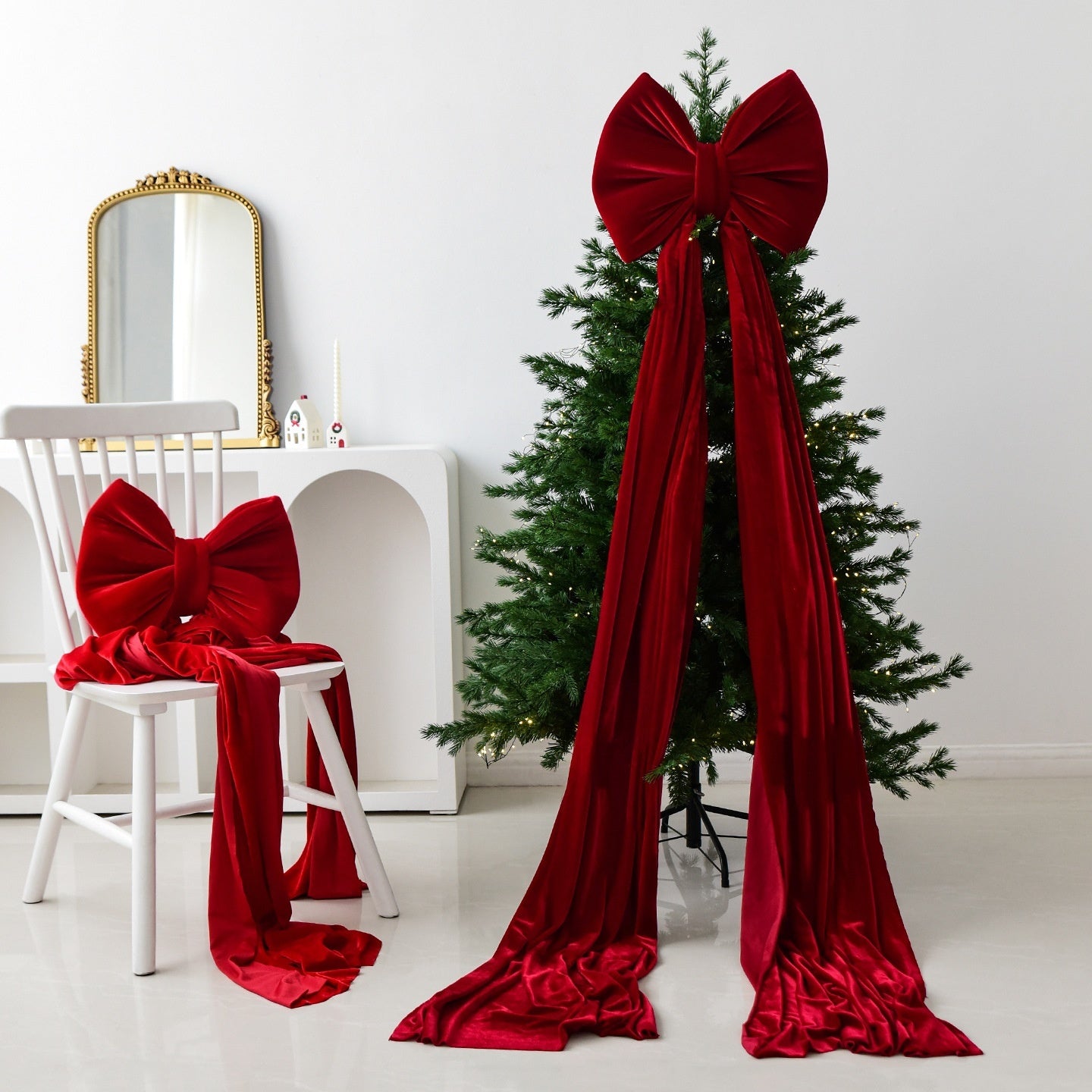 Christmas tree and chair decorated with large wine red velvet bows and long flowing ribbons in a minimalist room