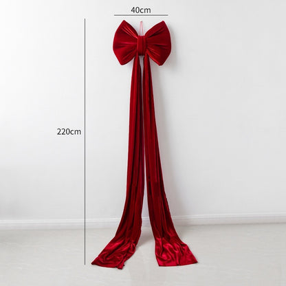 Large red velvet Christmas bow decoration with long flowing tails measuring 40cm by 220cm