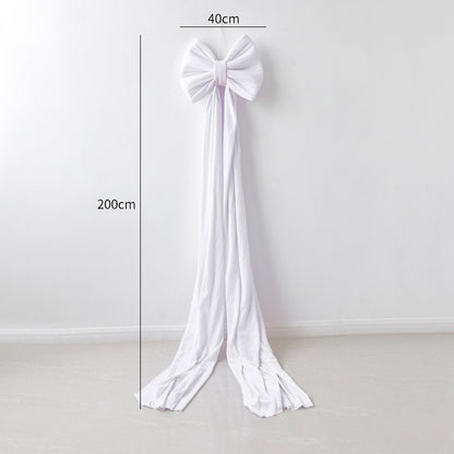 Large white fabric bow decoration measuring 40cm wide and 200cm long hanging on white wall