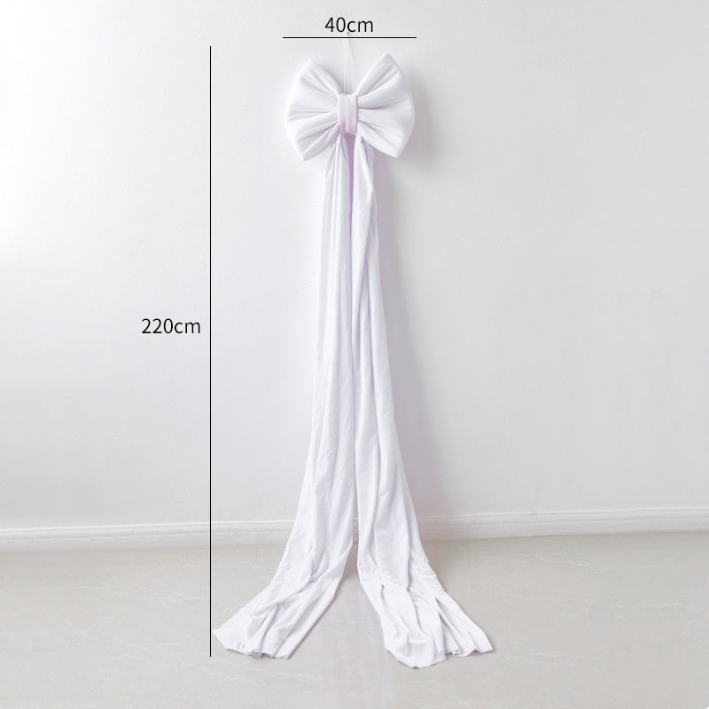 Large white decorative bow with long flowing tails hanging on a white wall, 40cm wide and 220cm long