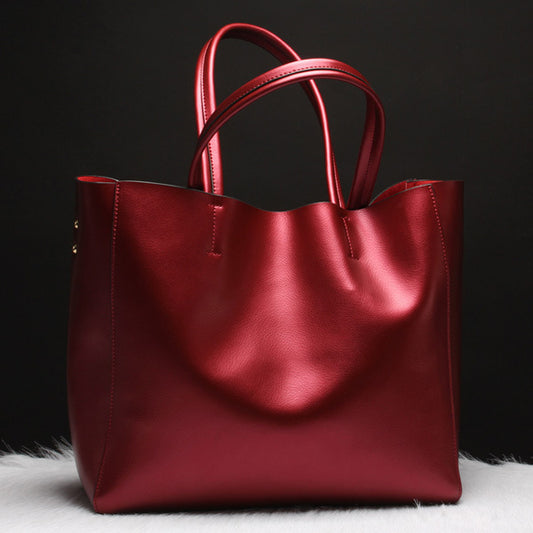 wine red cowhide leather tote bag with dual handles on white fur and black background