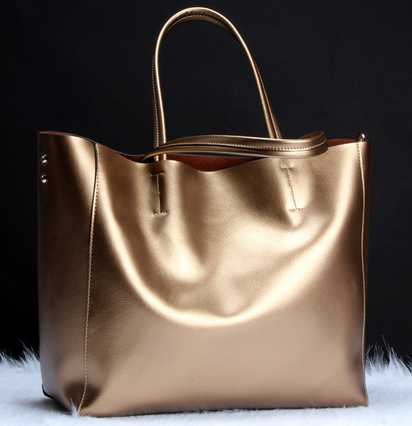 metallic gold leather tote bag with shoulder strap against black background