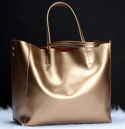 metallic gold leather tote bag with shoulder strap against black background