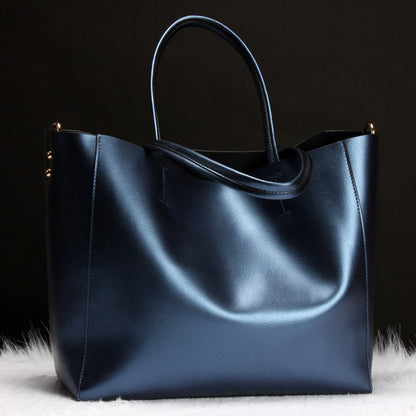 sleek black leather tote bag with double handles on white fur against dark background