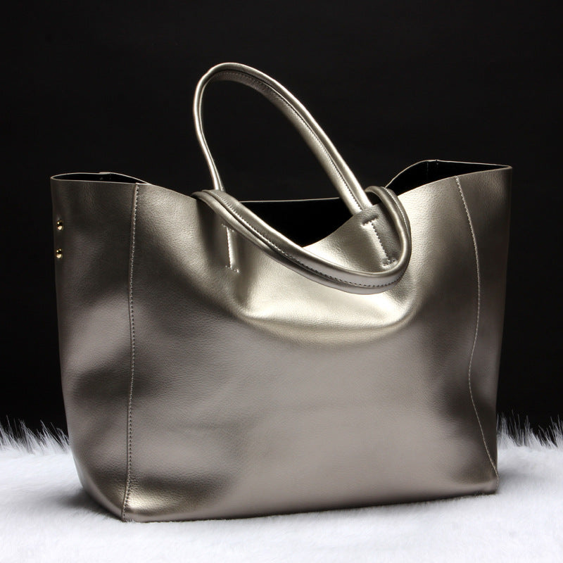 Metallic silver cowhide leather tote bag with double handles on white fur and black background