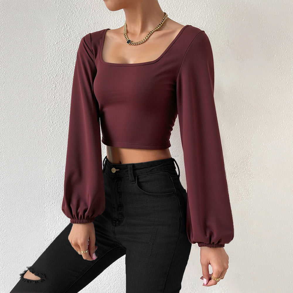 Woman wearing a wine red long lantern sleeve slim fit crop top with black high-waisted jeans