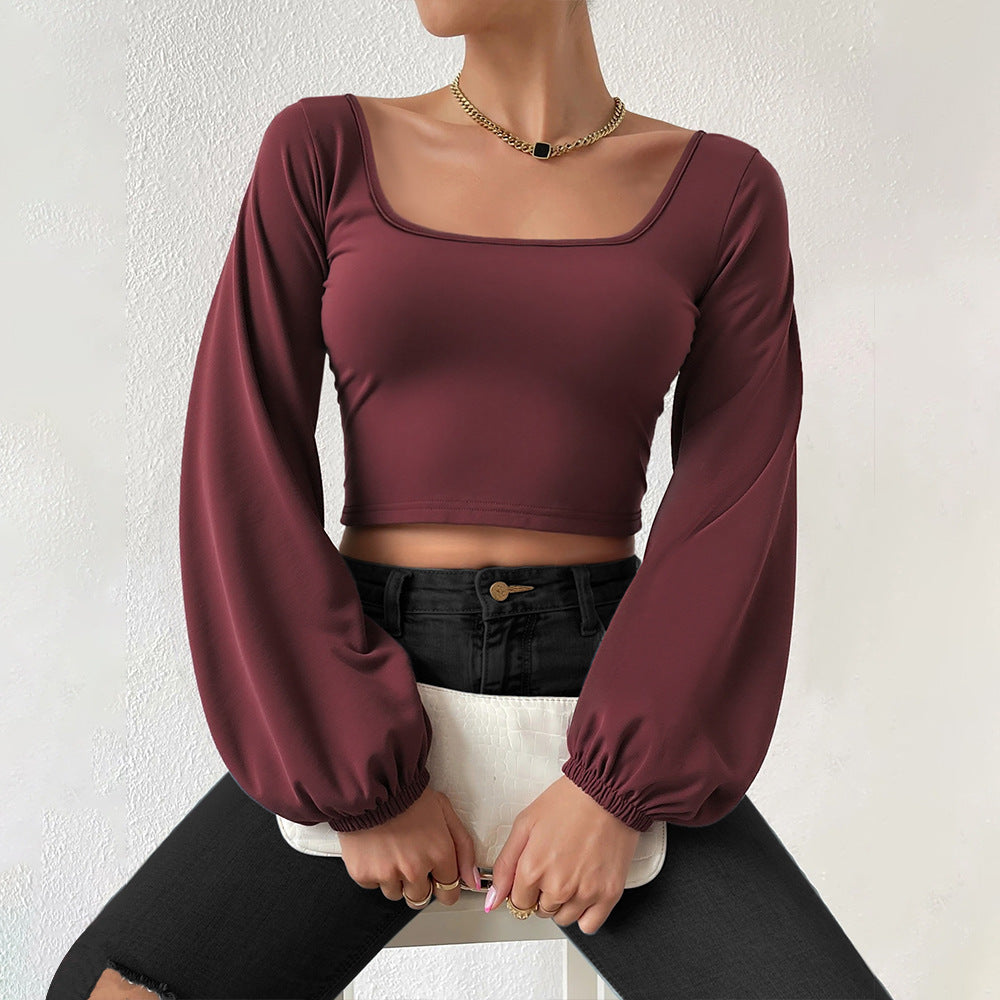 Woman wearing a wine red slim fit cropped top with lantern sleeves and black ripped jeans