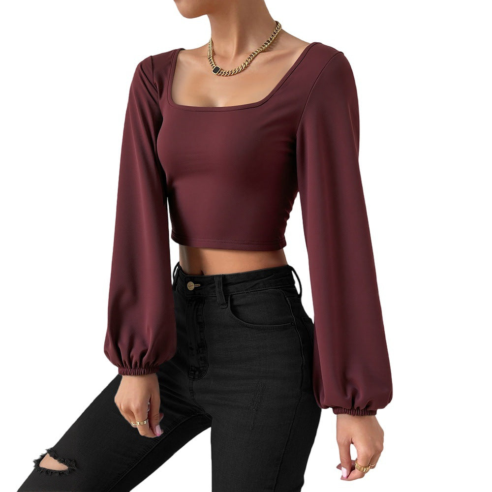 Woman wearing wine red lantern sleeve slim fit cropped top with black high waist ripped jeans