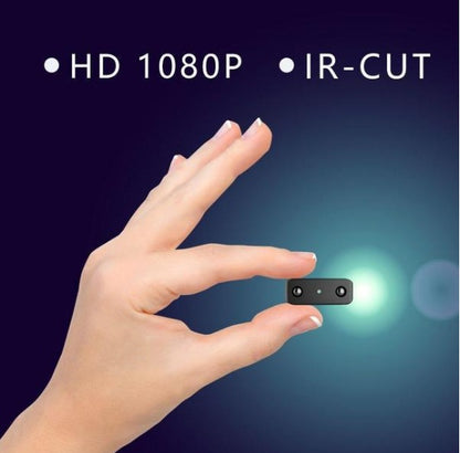 Hand holding a tiny black mini camera with HD 1080P and IR-CUT features on a dark blue background