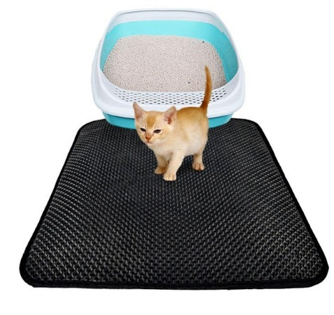 Small orange kitten on a black waterproof cat litter mat in front of a blue and white litter box