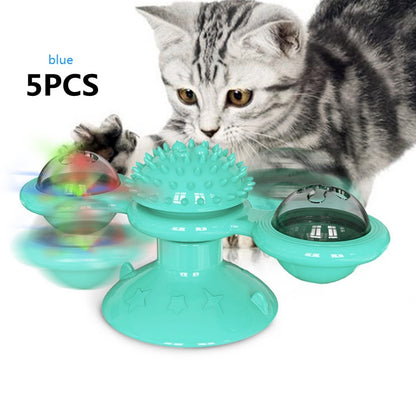 Gray tabby cat playing with blue interactive cat toy with spinning parts and suction base