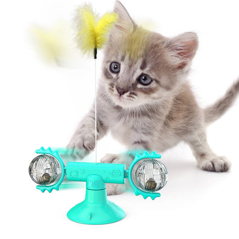 Gray kitten playing with blue interactive cat toy featuring rotating balls and yellow feather