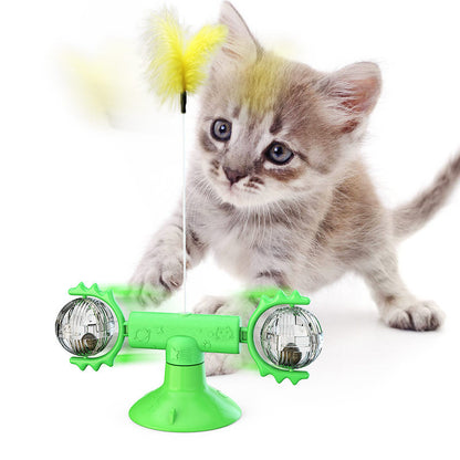 Cute gray tabby kitten playing with green interactive catnip suction cup toy with feather