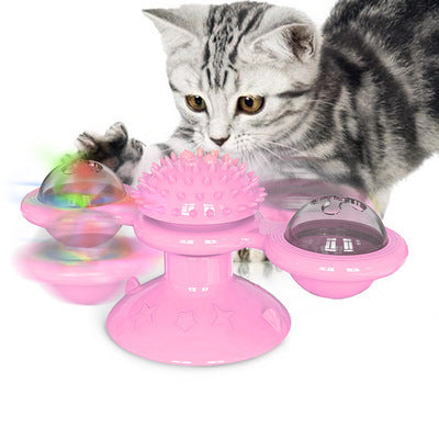 Gray tabby kitten playing with pink interactive cat toy with spinning sections and suction base