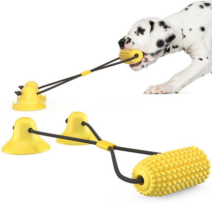 Dalmatian dog playing with durable yellow corn-shaped interactive dental chew toy attached to suction cups