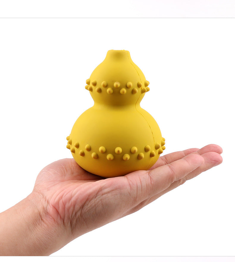 Hand holding a yellow, double-gourd shaped dog treat dispensing toy with raised nubs