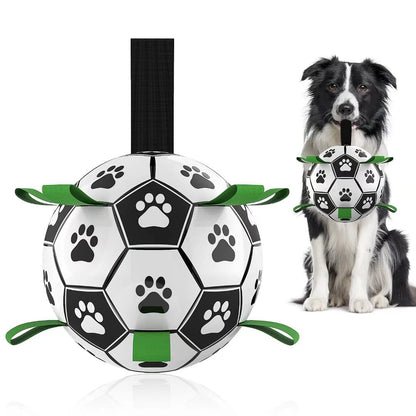 Durable black and white dog football toy with paw prints and green handles, held by a black and white Border Collie
