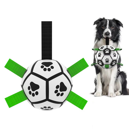 Durable white and black dog football toy with green handles and paw print design held by black and white Border Collie