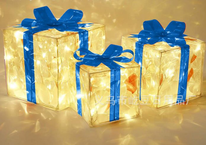 Three glowing Christmas gift boxes with blue ribbons illuminated with warm lights