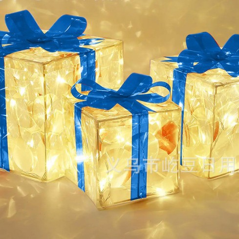 Luminous Christmas gift boxes with blue ribbons glowing with warm white lights on gold background