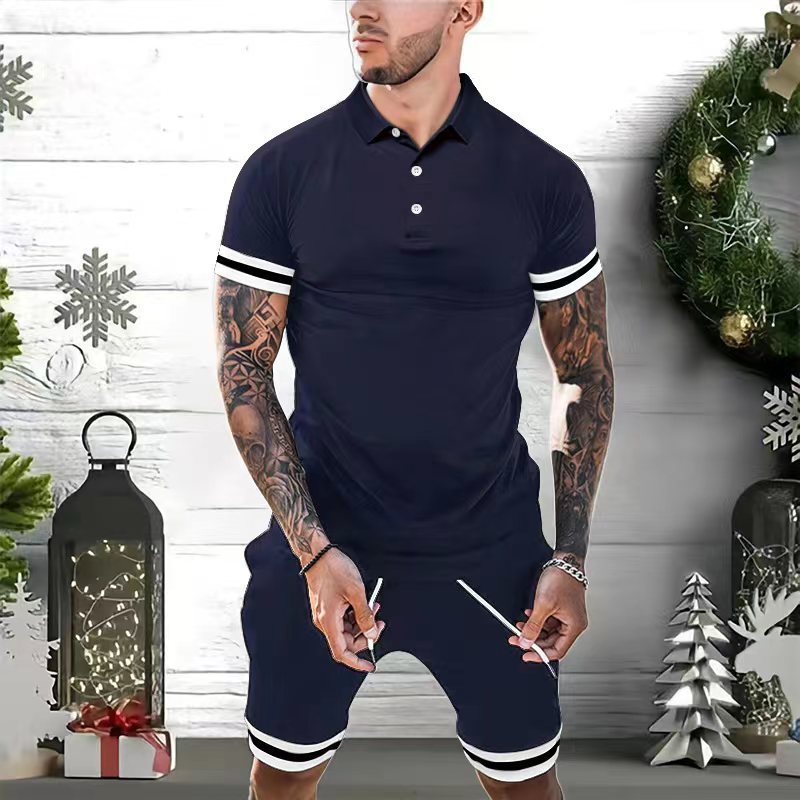 man wearing navy blue athletic polo shirt and shorts with white stripes, standing by Christmas decorations