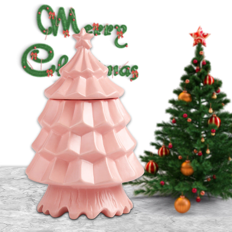 pink ceramic Christmas tree container with star topper and decorated green Christmas tree in background