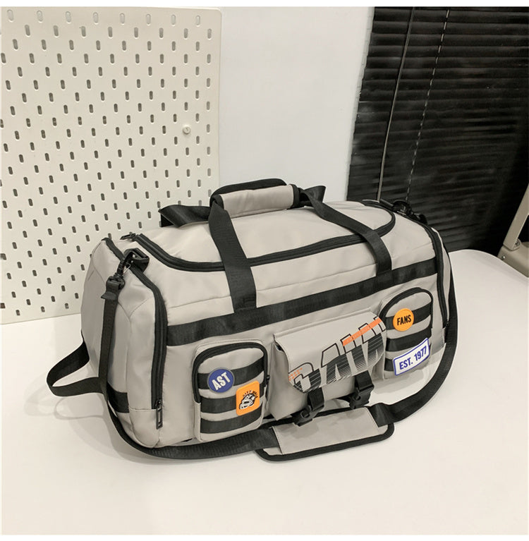 Beige and black duffel bag with multiple front pockets and patches placed on white surface