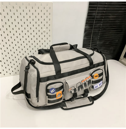 Beige and black duffel bag with multiple front pockets and patches placed on white surface
