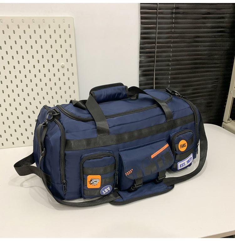 Navy blue multifunctional travel duffle bag with black straps and front pockets with patches on white surface