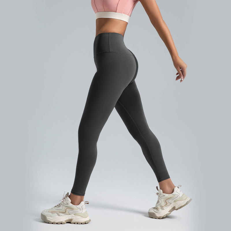 Woman wearing black high-waist tummy control leggings and white chunky sneakers, side view