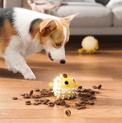 Corgi dog interacting with yellow pufferfish-shaped treat dispensing chew toy on wooden floor with scattered treats