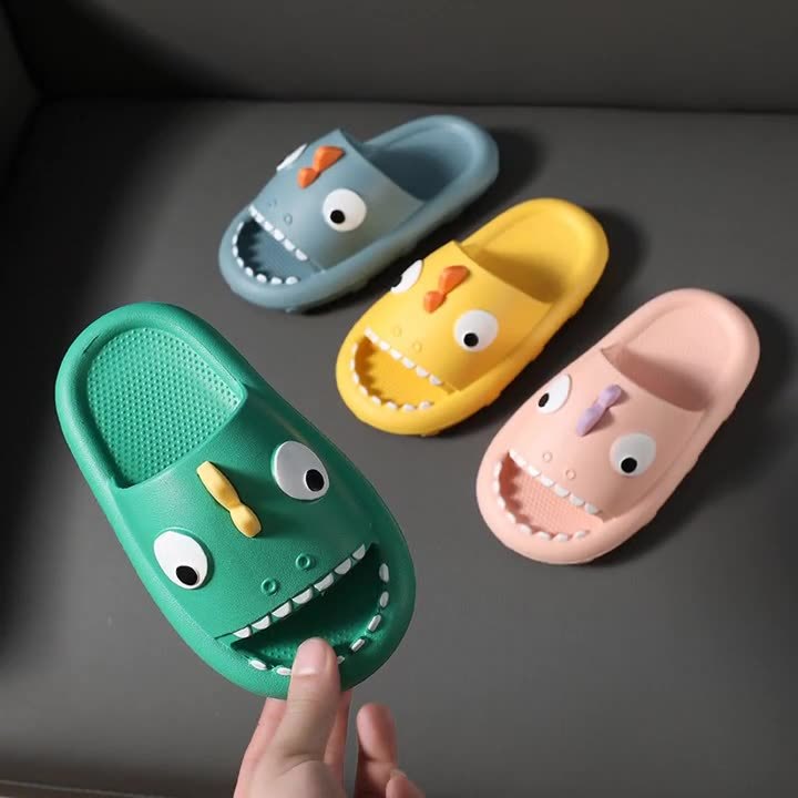 Colorful kids shark slippers in green, blue, yellow, and pink with non-slip soles on gray background