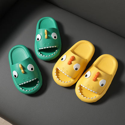 Green and yellow kids cartoon dinosaur slippers with big eyes and teeth on gray background