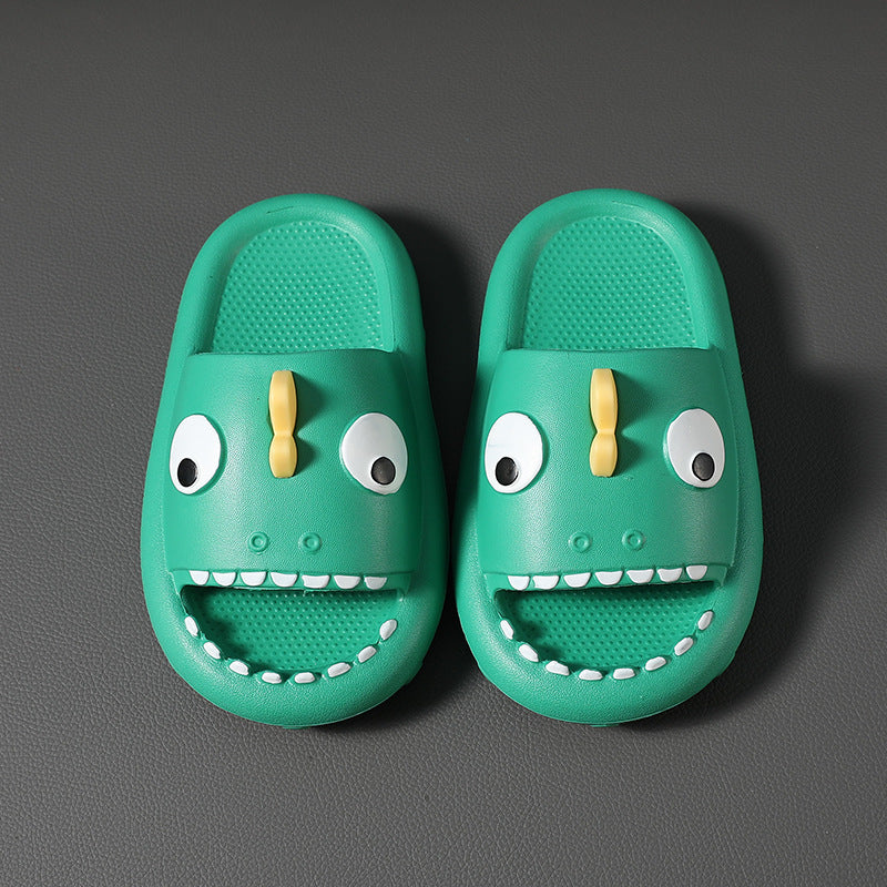 Green kids dinosaur slippers with big eyes and teeth, non-slip indoor shoes on dark surface