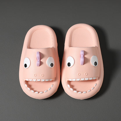 Pink kids shower slippers with cartoon dinosaur faces and non-slip textured soles on gray surface