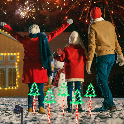 Family in winter clothes watching fireworks by snowman and solar-powered Christmas tree pathway lights
