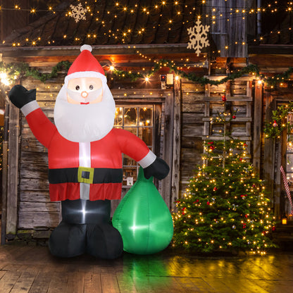 Inflatable 6ft LED Santa Claus decoration with green gift bag next to lit Christmas tree by wooden cabin