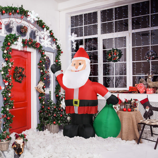 Indoor Christmas scene with 6ft inflatable Santa holding a green bag, red door, wreath, and festive decorations