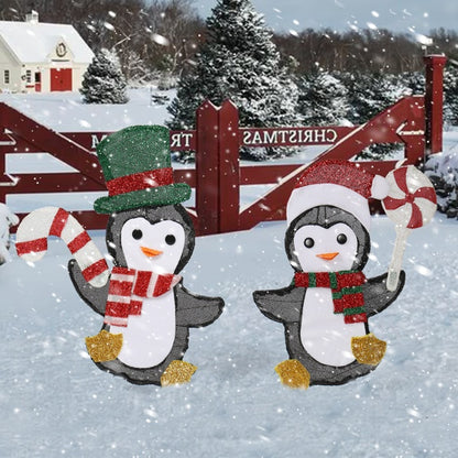 Two glittery penguin Christmas lights in snow, one with green top hat the other with Santa hat, holding candy cane and peppermint