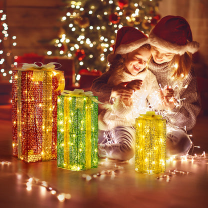 Mother and daughter in Santa hats with warm white LED lighted gift boxes by Christmas tree