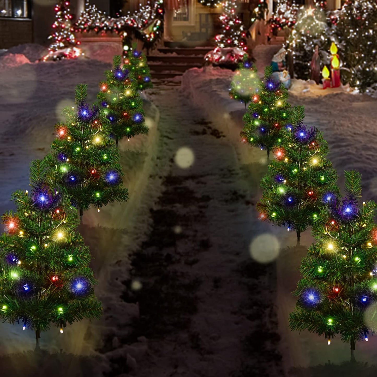 Snowy pathway lined with small multicolored LED-lit Christmas trees, festive outdoor holiday decor