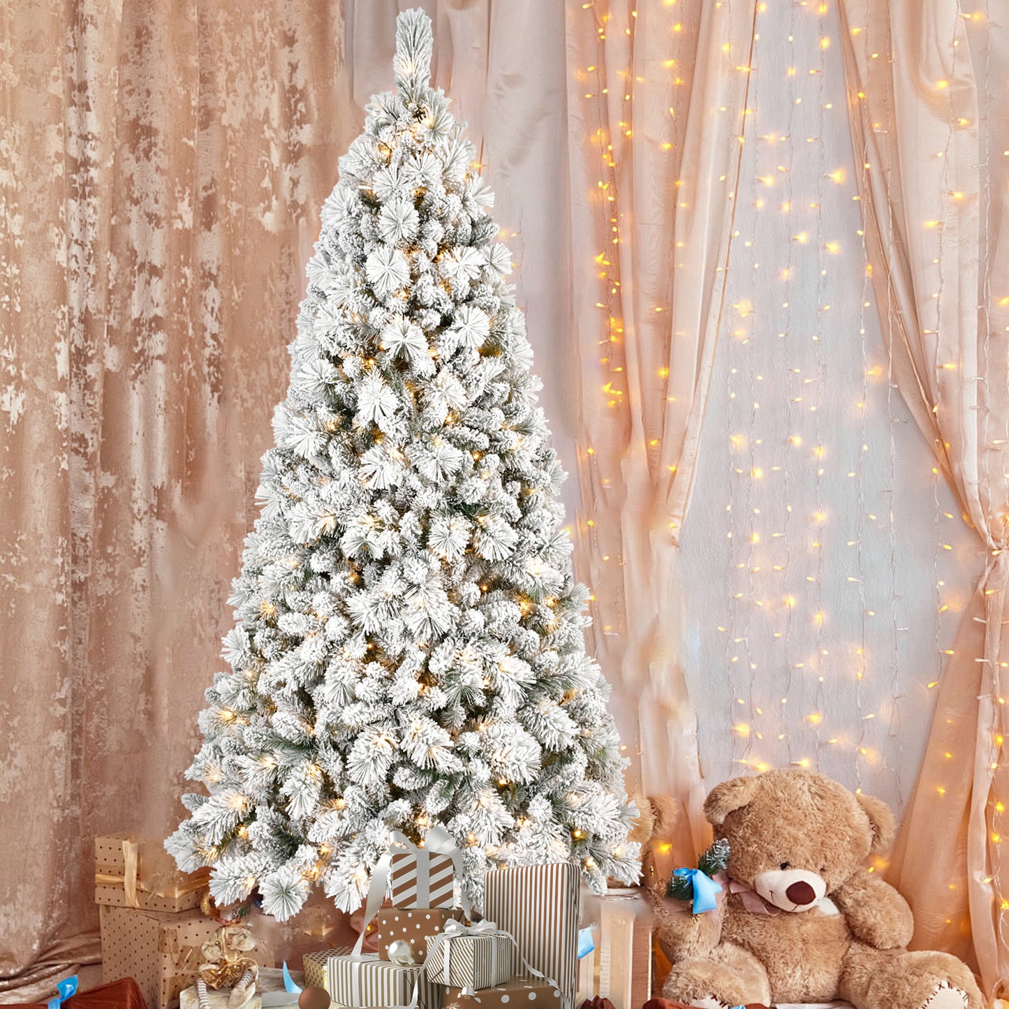 Flocked PVC Christmas tree with warm white LED lights surrounded by wrapped gifts and a large teddy bear