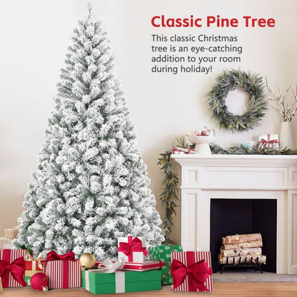 Snow flocked artificial Christmas pine tree decorated with presents near a white fireplace and wreath