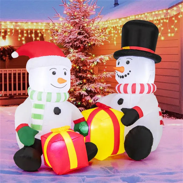Inflatable Christmas snowmen with LED lights holding gift boxes in snowy yard with festive string lights