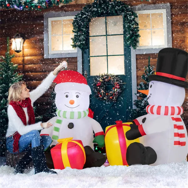 Woman adjusting 5ft inflatable snowman with red Santa hat and gift boxes in snowy Christmas outdoor scene