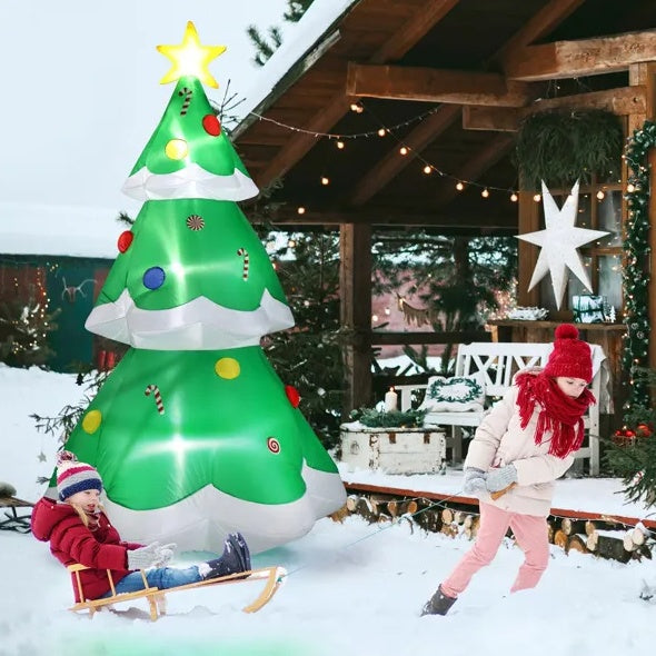 Children playing in snow near 6-9 ft inflatable LED Christmas tree with candy decorations and lit star