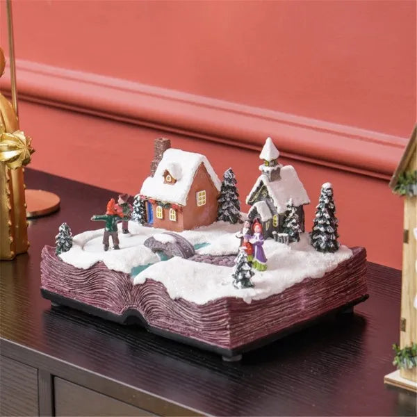 Animated musical LED Christmas village decoration with snow-covered houses, trees, and figurines on book-shaped base
